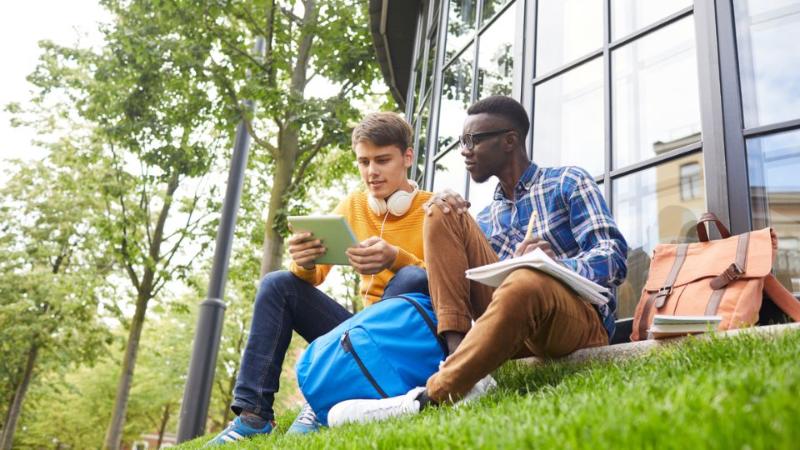 two male students sitting chatting outside